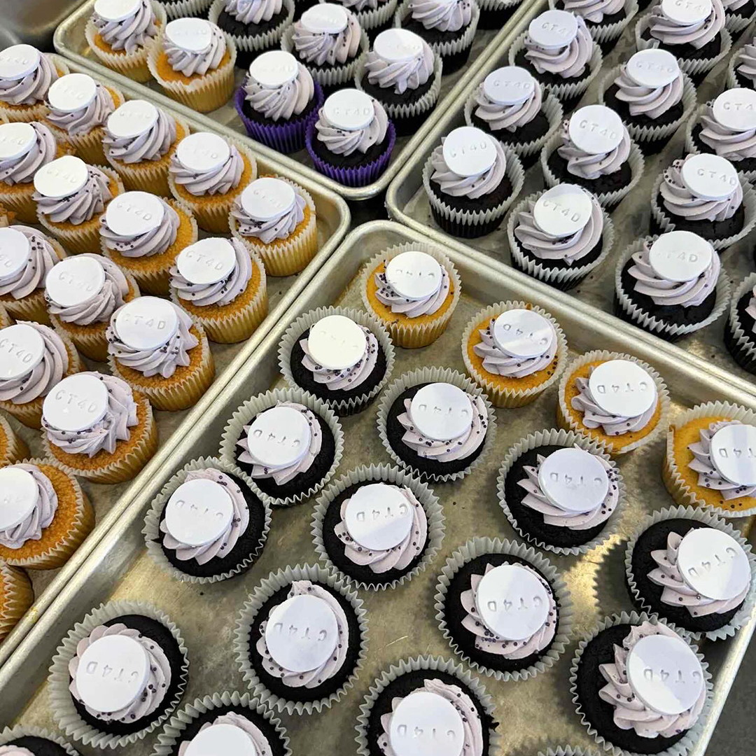 A bird's eye view of several trays of decorated cupcakes.