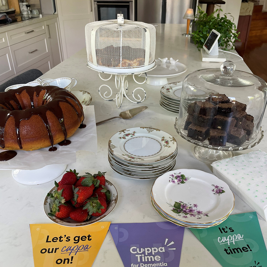 A table full of sweets, a Cuppatime bunting and a vase of flowers.