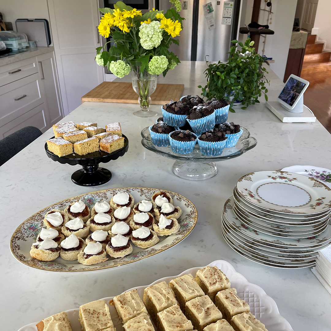 A table full of sweets and a vase of flowers.